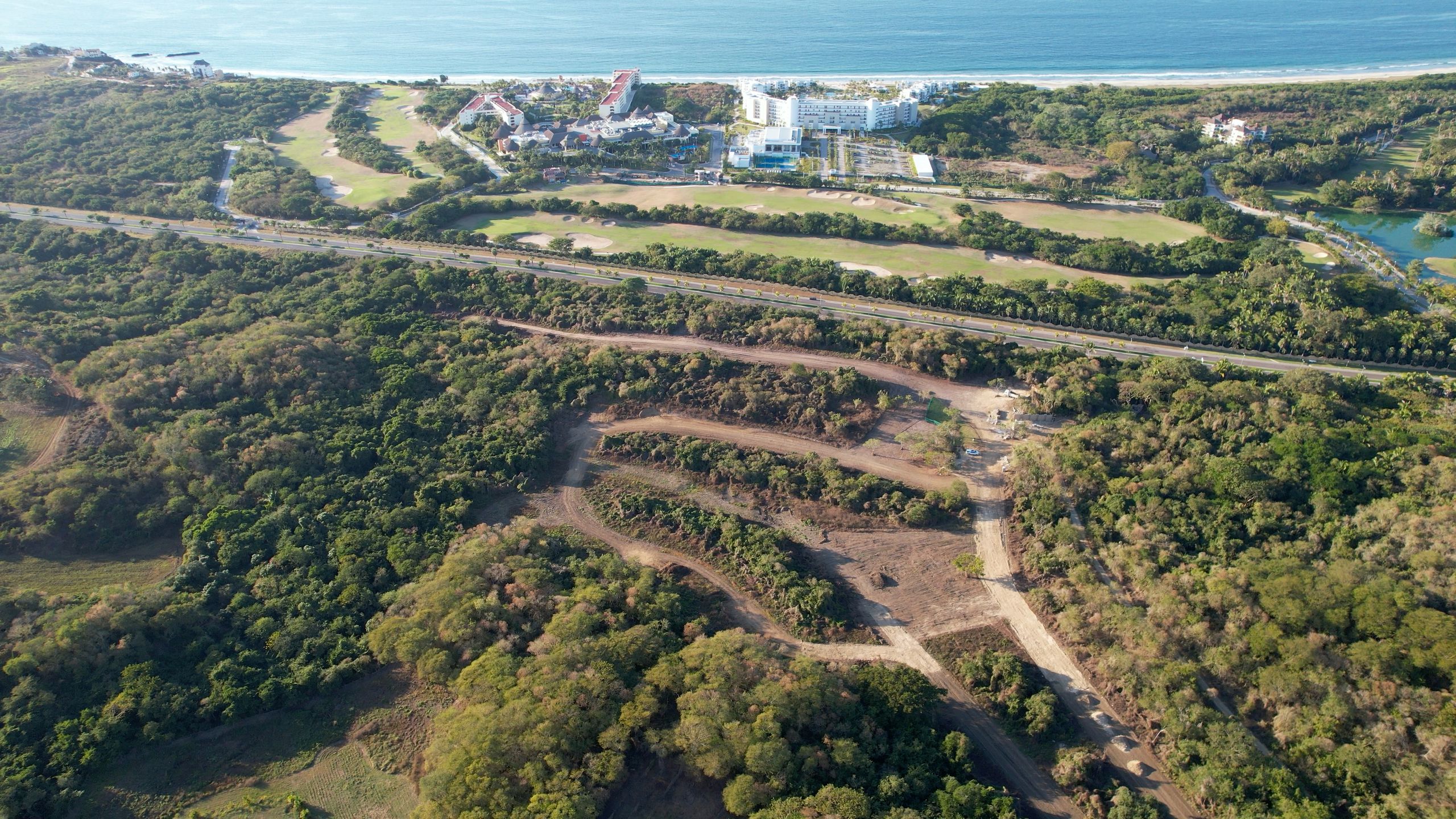 Vista aérea del terreno de Higuera Residence con Higuera Golf Club del otro lado de la carretera y el océano Pacífico al fondo